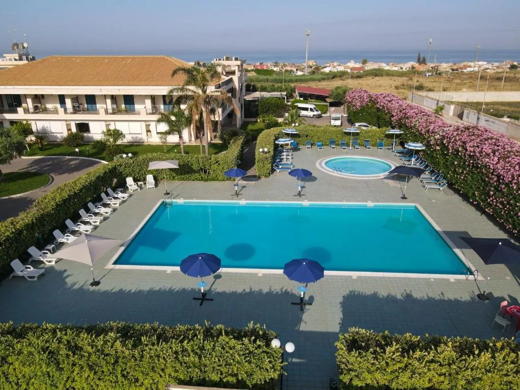 Vista dall'alto della piscina con lettini e ombrelloni e mare in lontananza