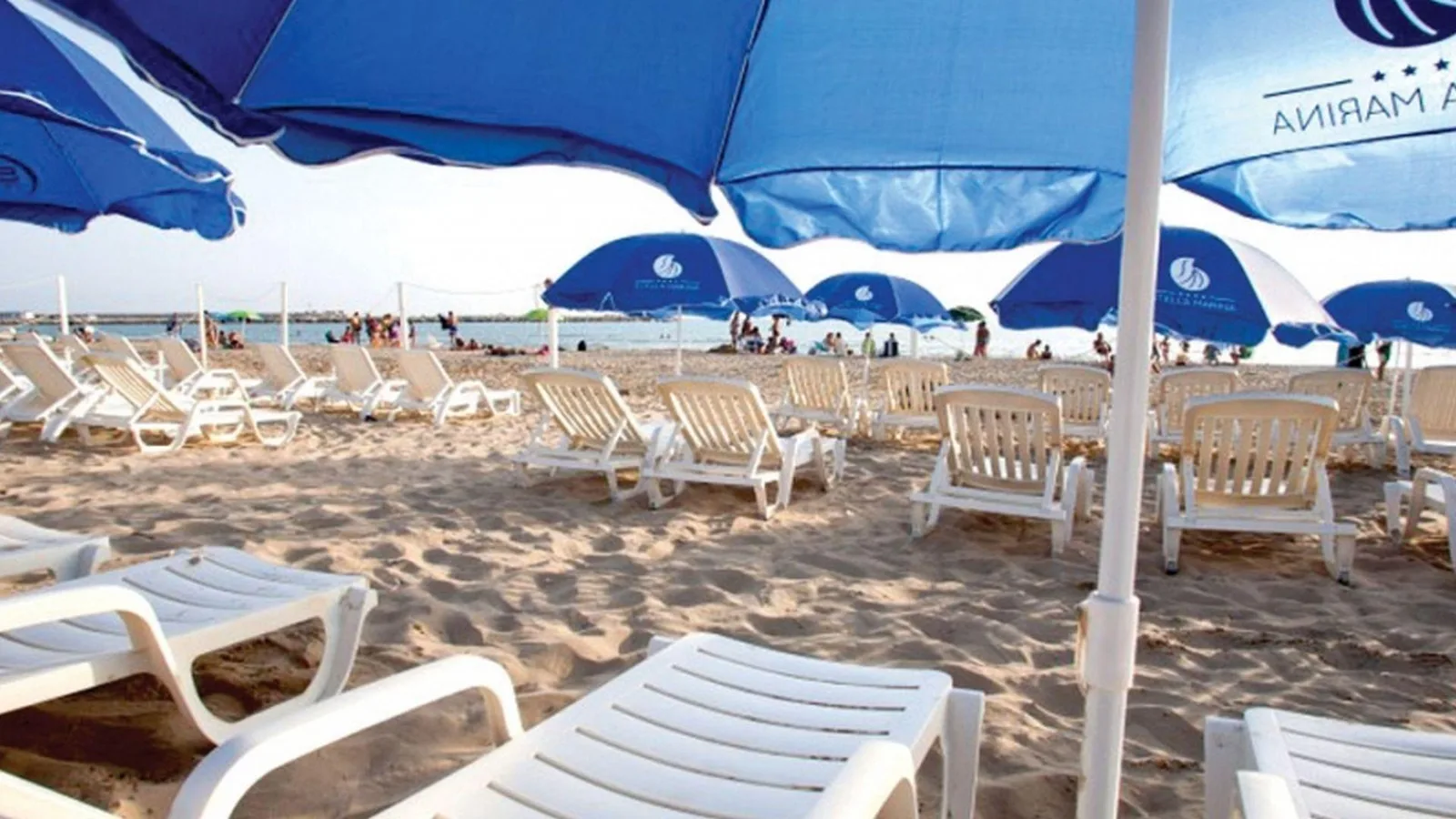 Spiaggia attrezzata con lettini bianchi e ombrelloni blu
