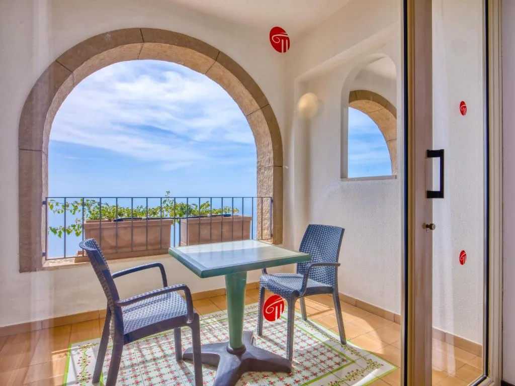 Balcone con tavolino, sedie e finestra ad arco affacciato sul mare