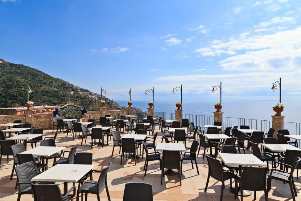 Ampia terrazza ristorante con tavoli e sedie e vista panoramica sul mare