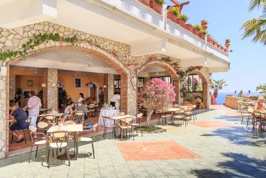 Terrazza esterna con archi in pietra, tavoli e fiori colorati