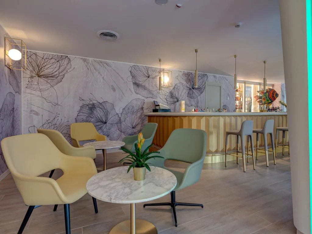 Bar interno con poltrone colorate, tavolini in marmo e bancone di design