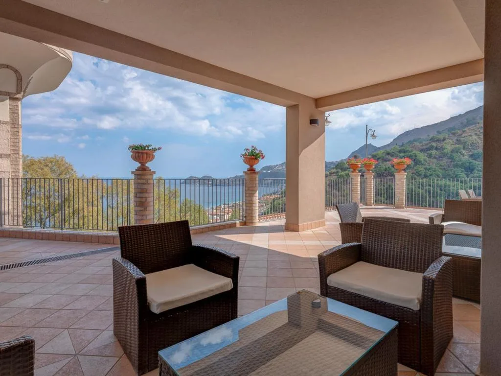 Terrazza coperta con poltrone in vimini e vista panoramica sulla baia