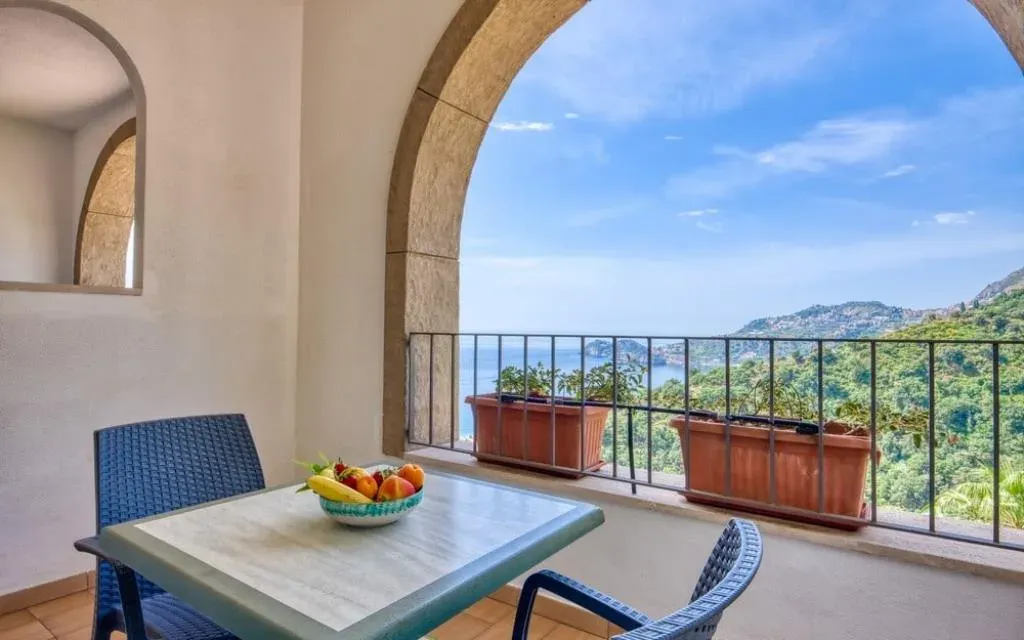 Balcone con tavolo e sedie affacciato sul mare attraverso archi in pietra