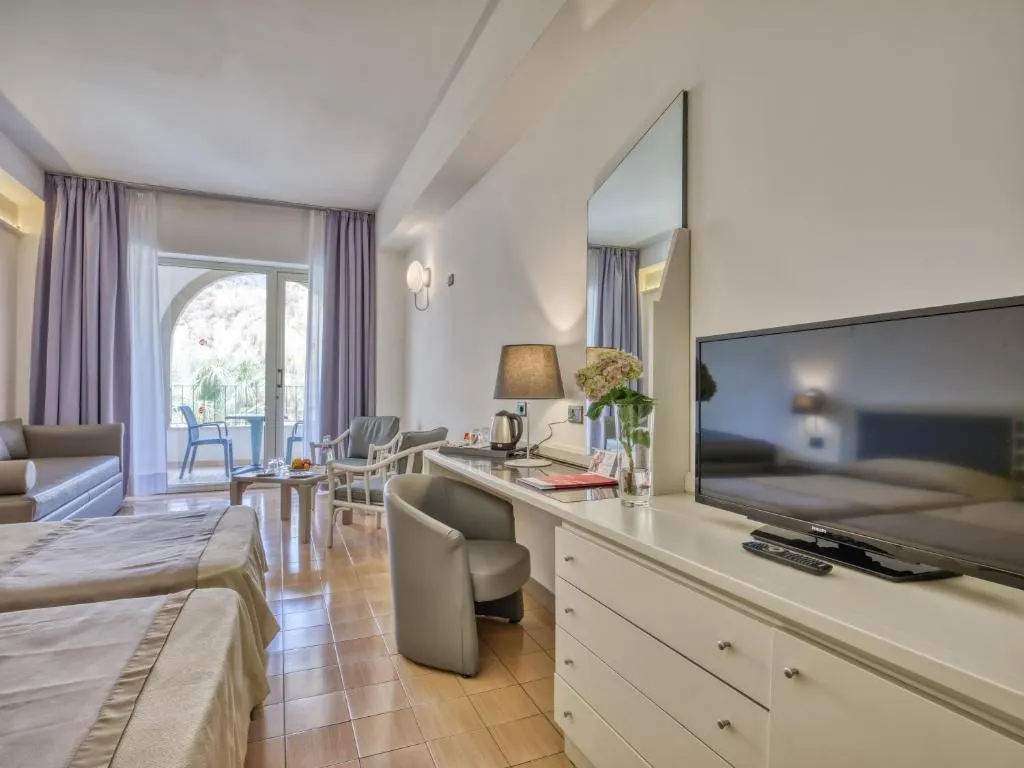 Camera luminosa con letto, TV, scrivania e accesso al balcone