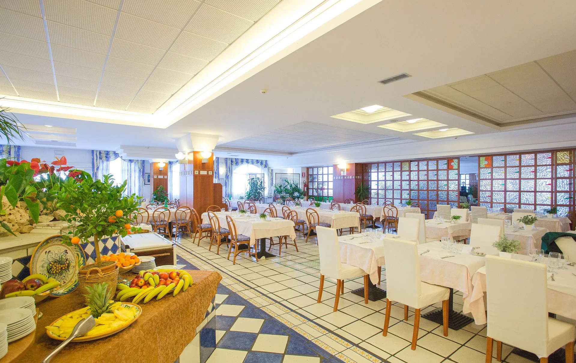 Sala ristorante luminosa con tavoli apparecchiati e pavimento a scacchi