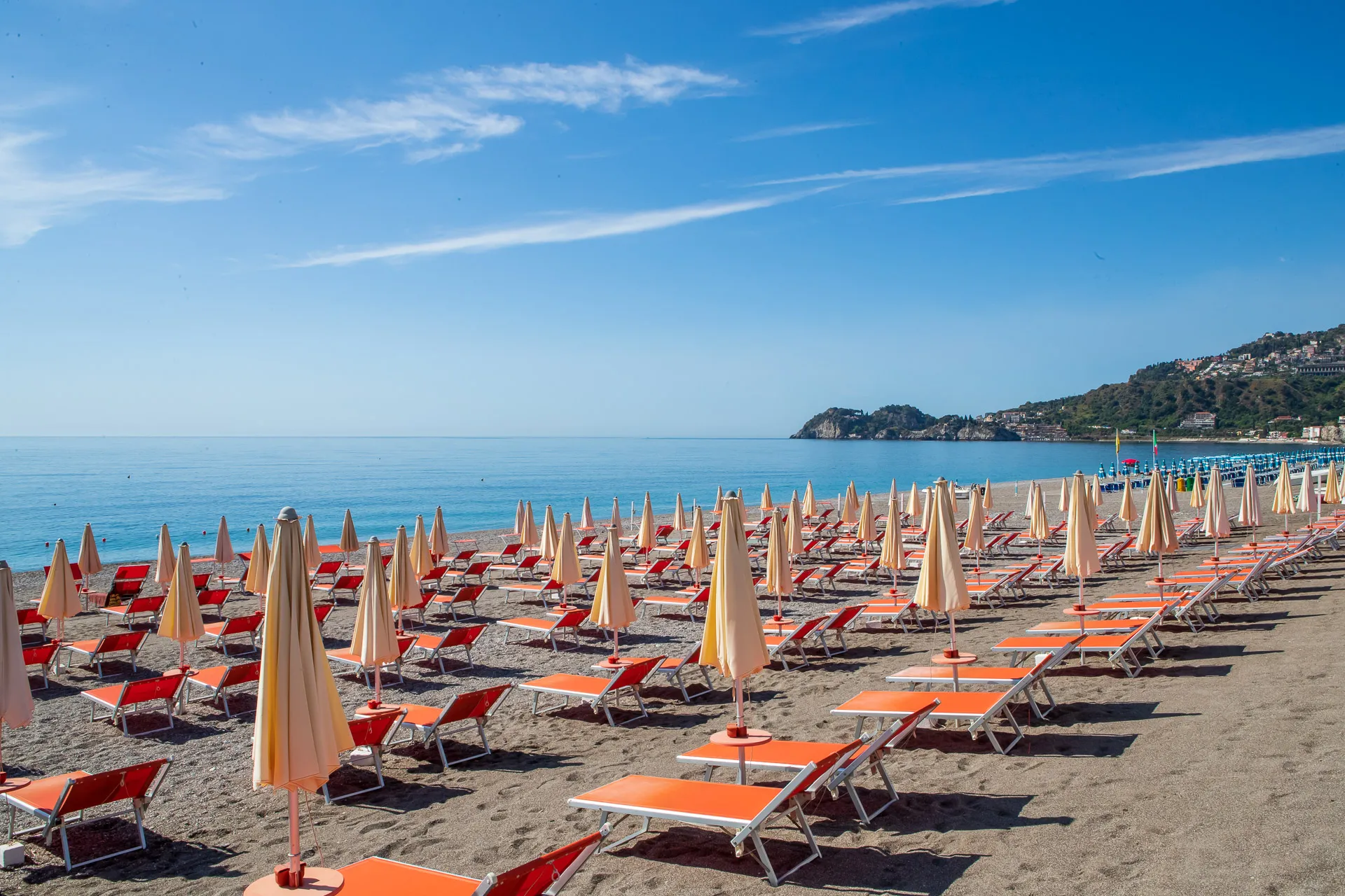 Spiaggia attrezzata con lettini arancioni e ombrelloni davanti al mare