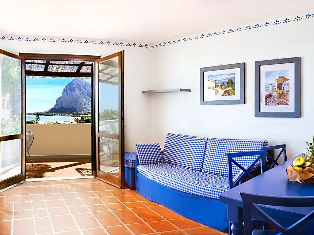 Salotto luminoso con divano a quadri blu e vista sul mare e la montagna