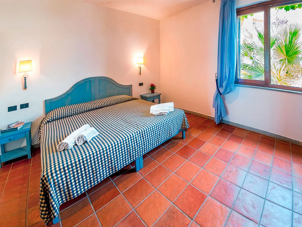 Camera da letto matrimoniale con pavimento in cotto e finestra sul verde