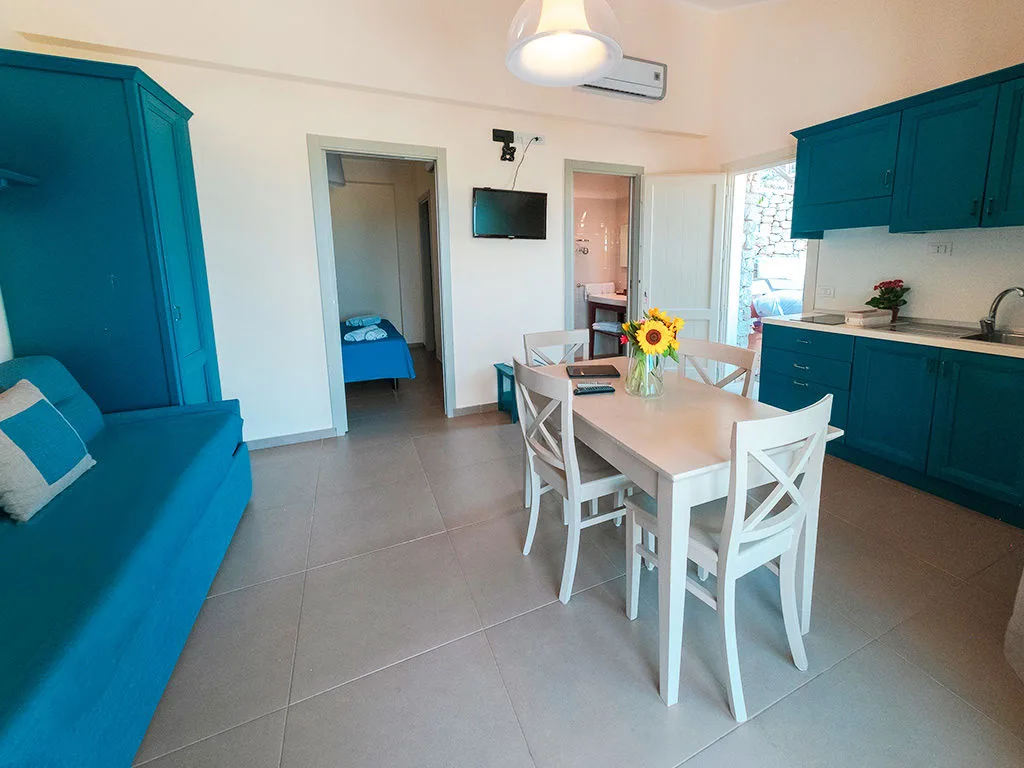 Soggiorno moderno con cucina blu, tavolo bianco e divano