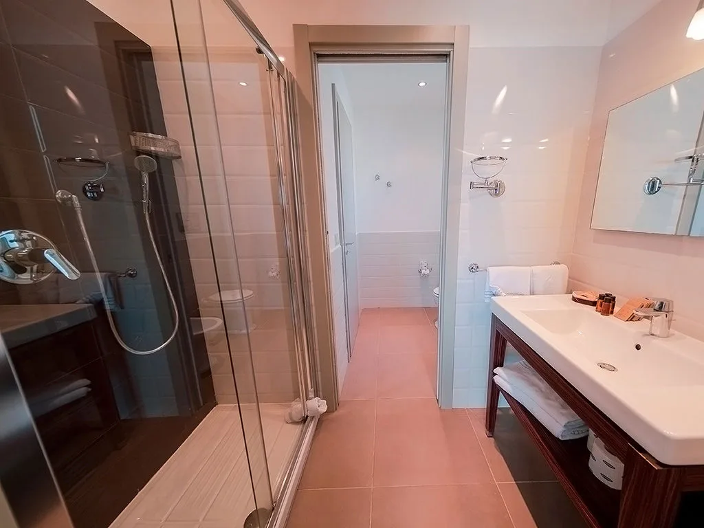 Bagno con doccia in vetro, lavabo e specchio