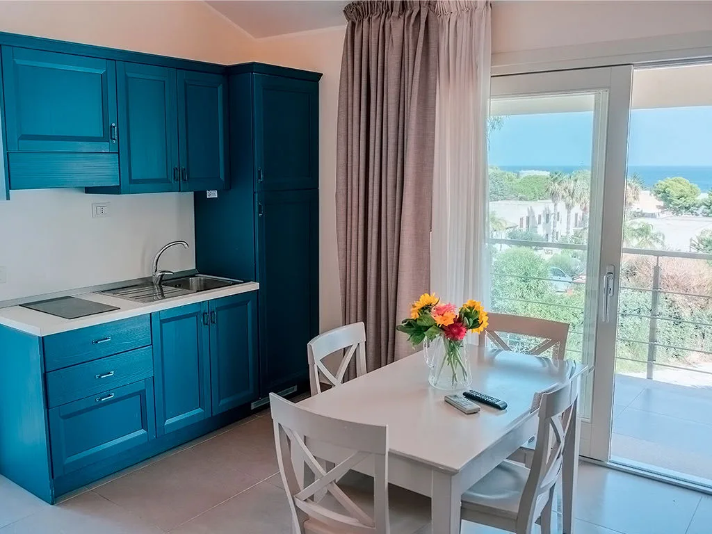 Angolo cucina blu con tavolo bianco e balcone con vista mare