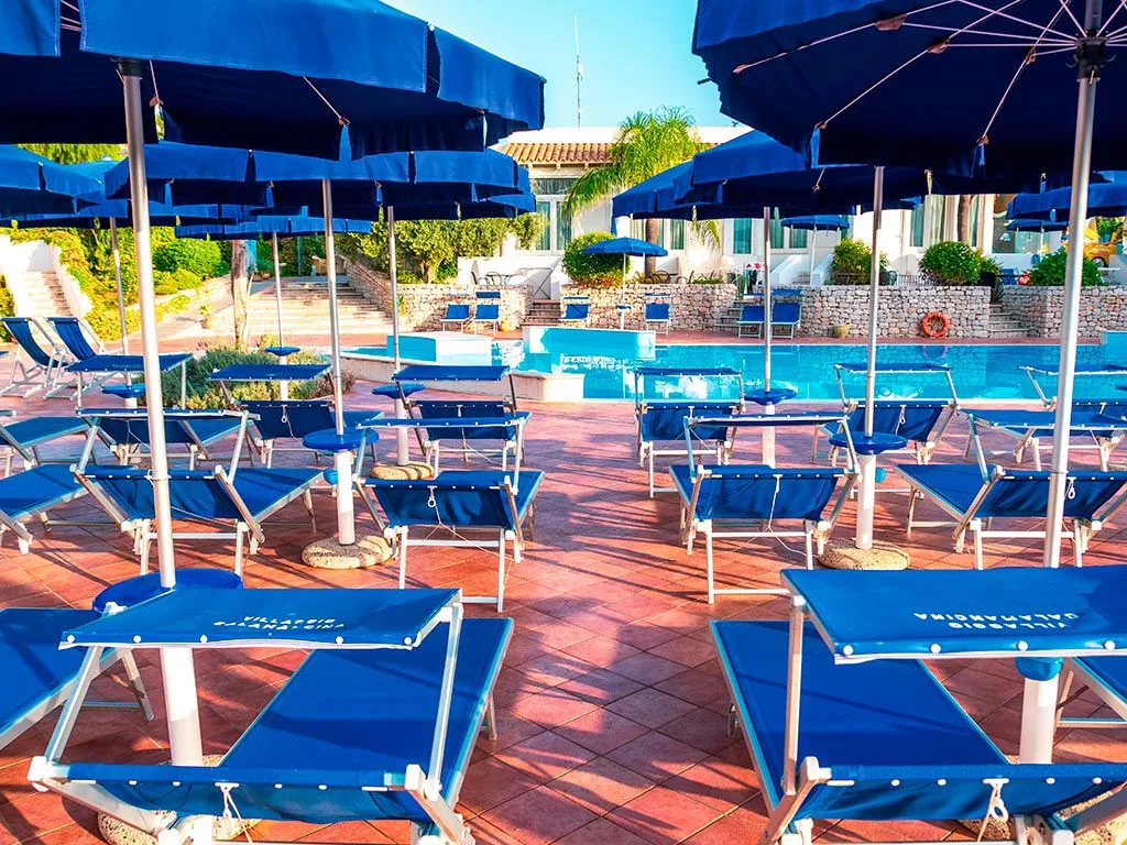 Lettini e ombrelloni blu a bordo piscina