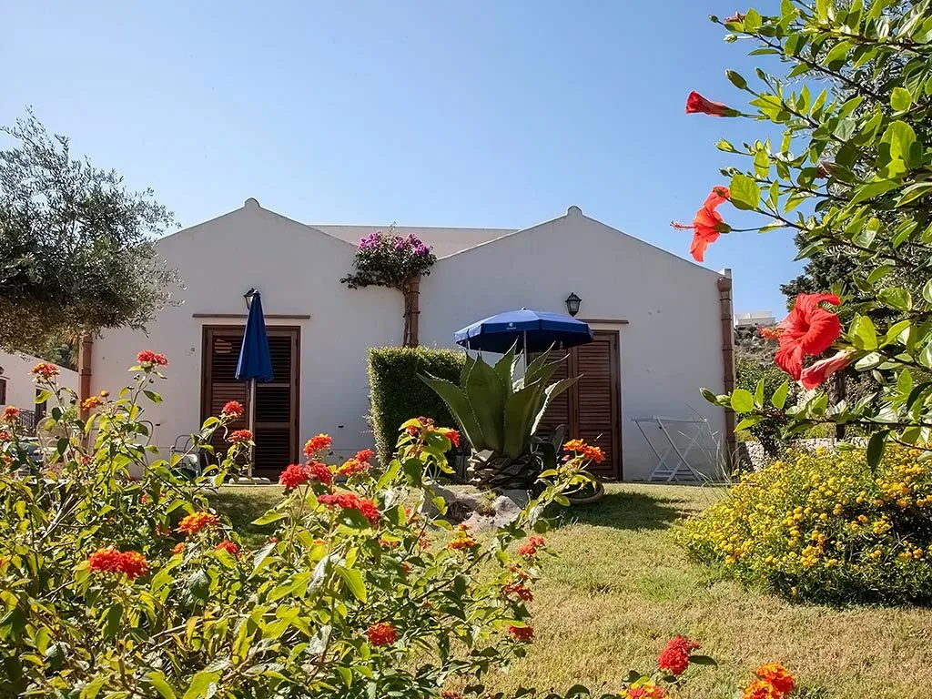 Bungalow bianco circondato da giardino fiorito con fiori colorati