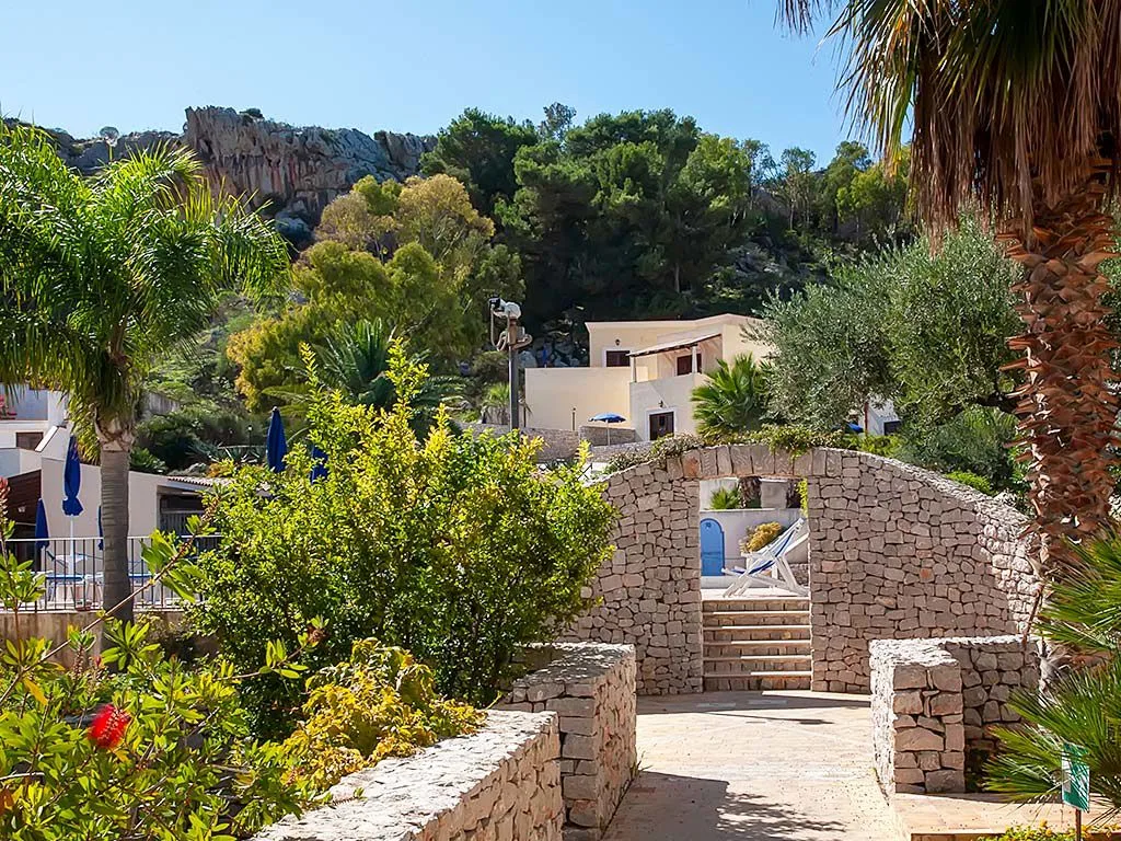 Vialetto in pietra tra il verde con archi e collina alle spalle