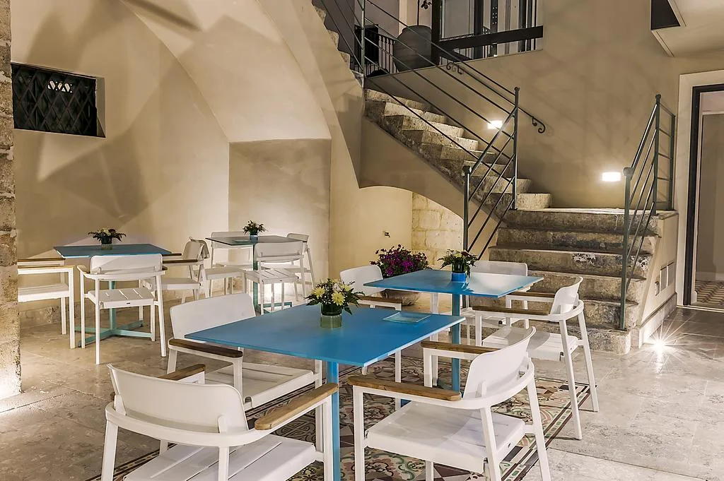 Sala colazione con tavoli azzurri, sedie bianche e scalinata in pietra