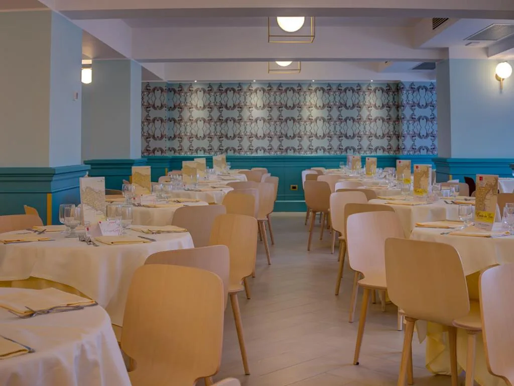 Sala ristorante interna con tavoli apparecchiati e pareti azzurre