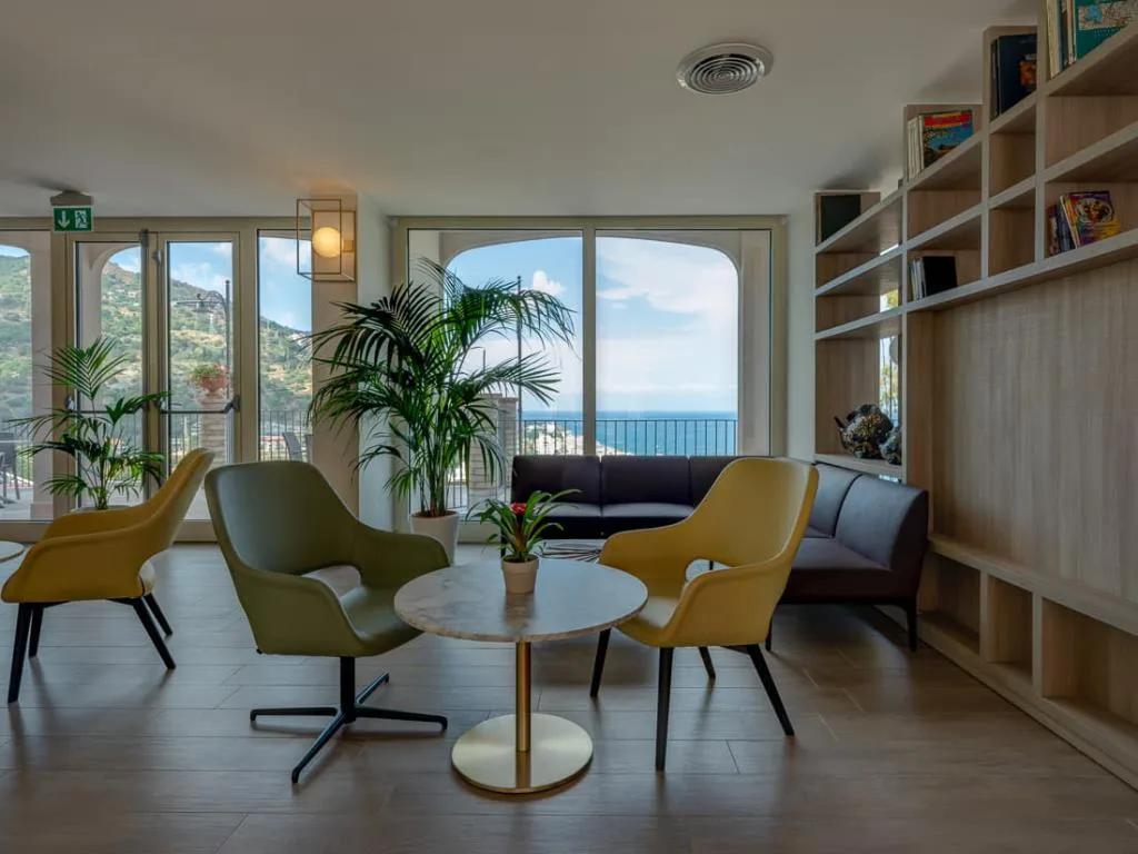 Area relax con poltrone colorate e vetrate affacciate su mare e colline