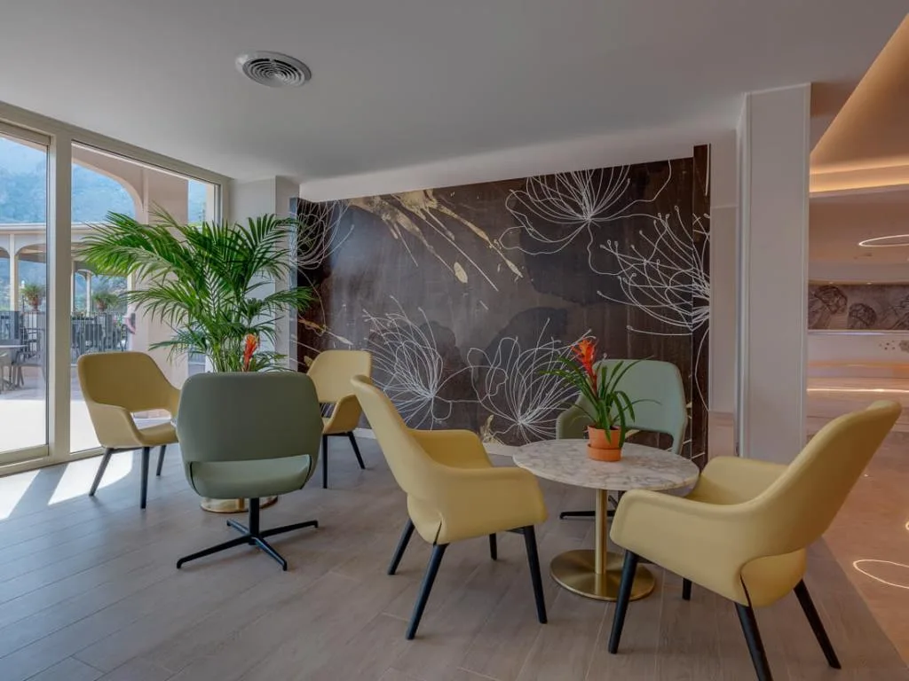 Zona lounge con poltrone gialle e verdi e parete decorativa floreale
