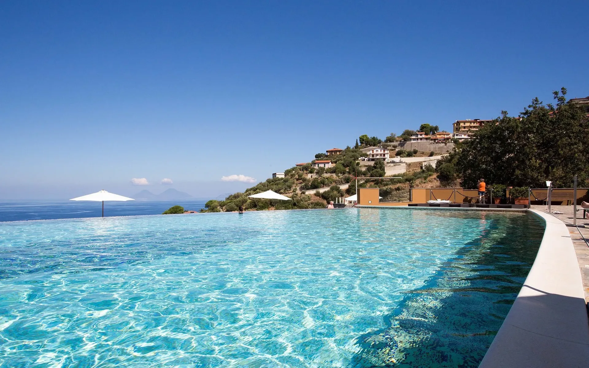 Piscina a sfioro con vista sul mare blu e sulle isole all'orizzonte