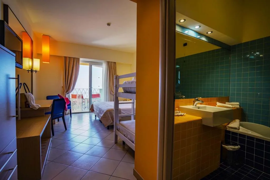 Camera con letto matrimoniale, letto a castello, scrivania e balcone vista mare