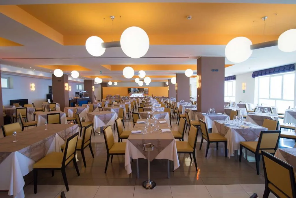 Sala ristorante interna con tavoli apparecchiati, sedie gialle e lampade a sfera