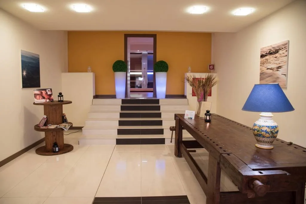 Hall dell'hotel con scalinata, tavolo in legno e lampada decorata in ceramica