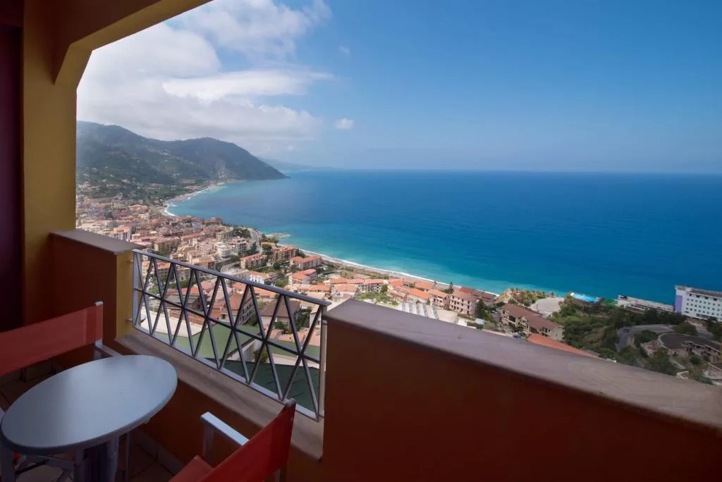 Balcone con tavolino e sedie e vista panoramica sulla costa e sul mare blu