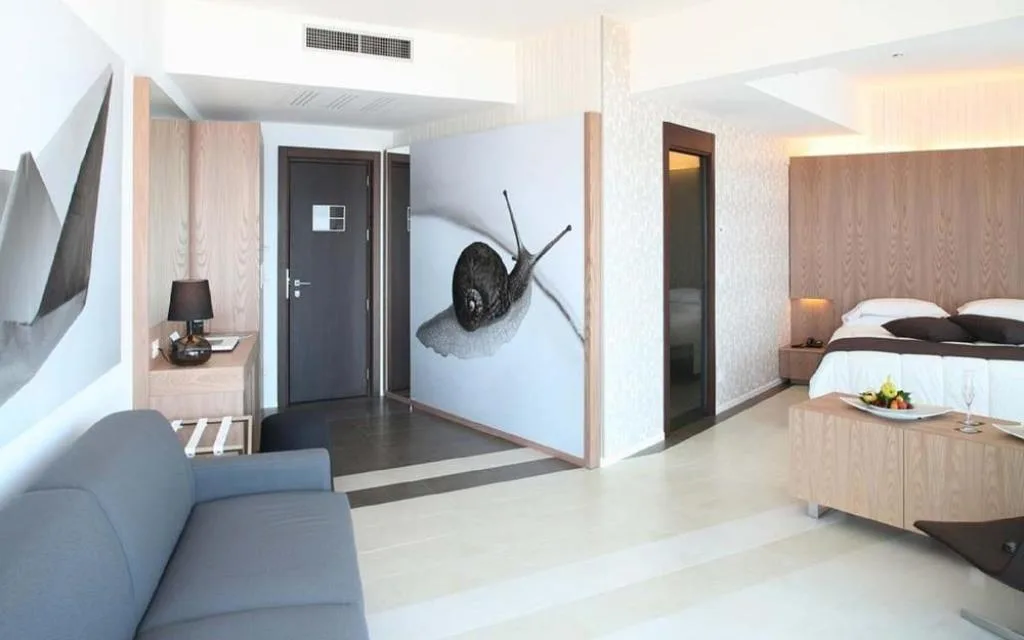 Suite spaziosa con divano grigio, letto matrimoniale e decorazione artistica a parete