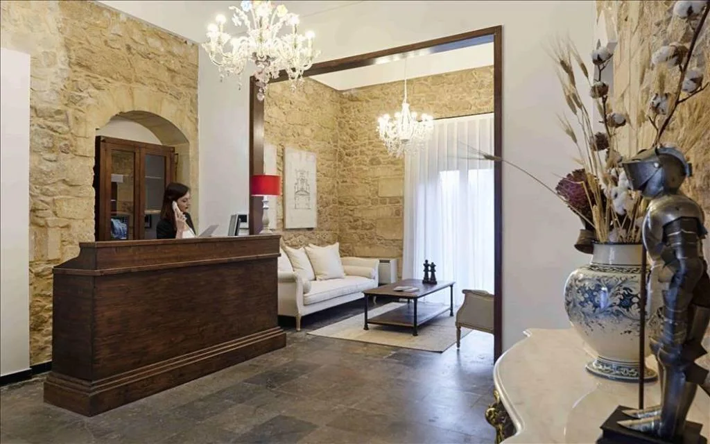 Hall con reception in legno, pareti in pietra, lampadari di cristallo e divano bianco