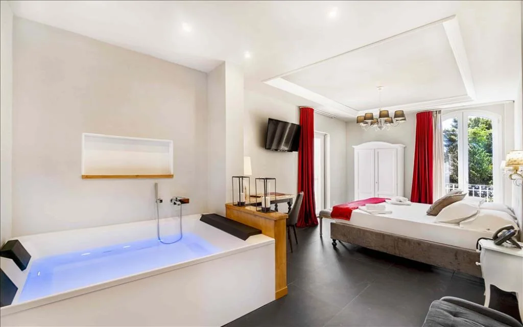 Ampia suite con vasca idromassaggio, letto matrimoniale, tende rosse e accesso al balcone