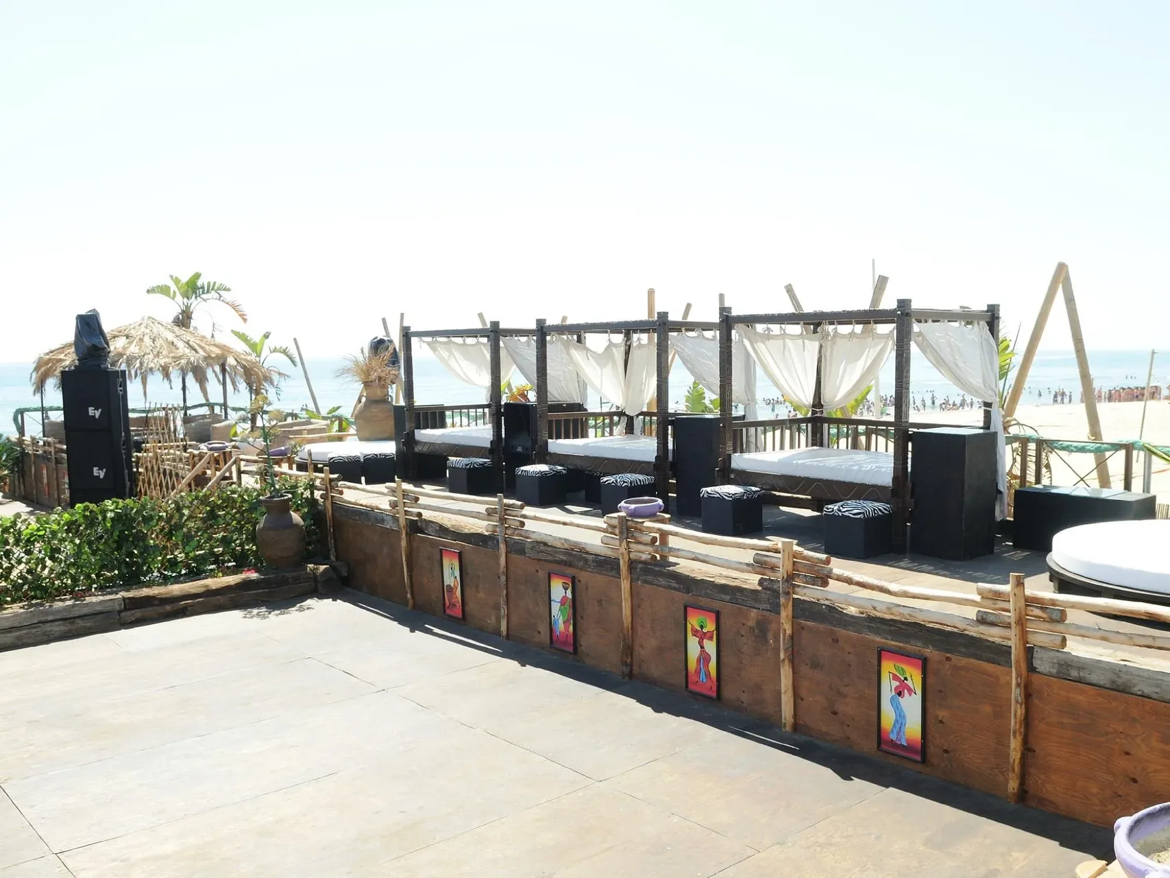 Area lounge con letti baldacchino e tende bianche vista mare in beach club
