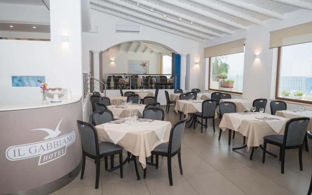 Sala ristorante dell'Hotel Il Gabbiano con tavoli e grandi finestre