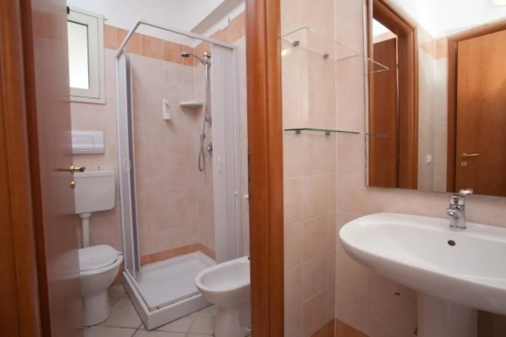 Bagno con doccia, lavabo, wc e bidet con piastrelle color pesca