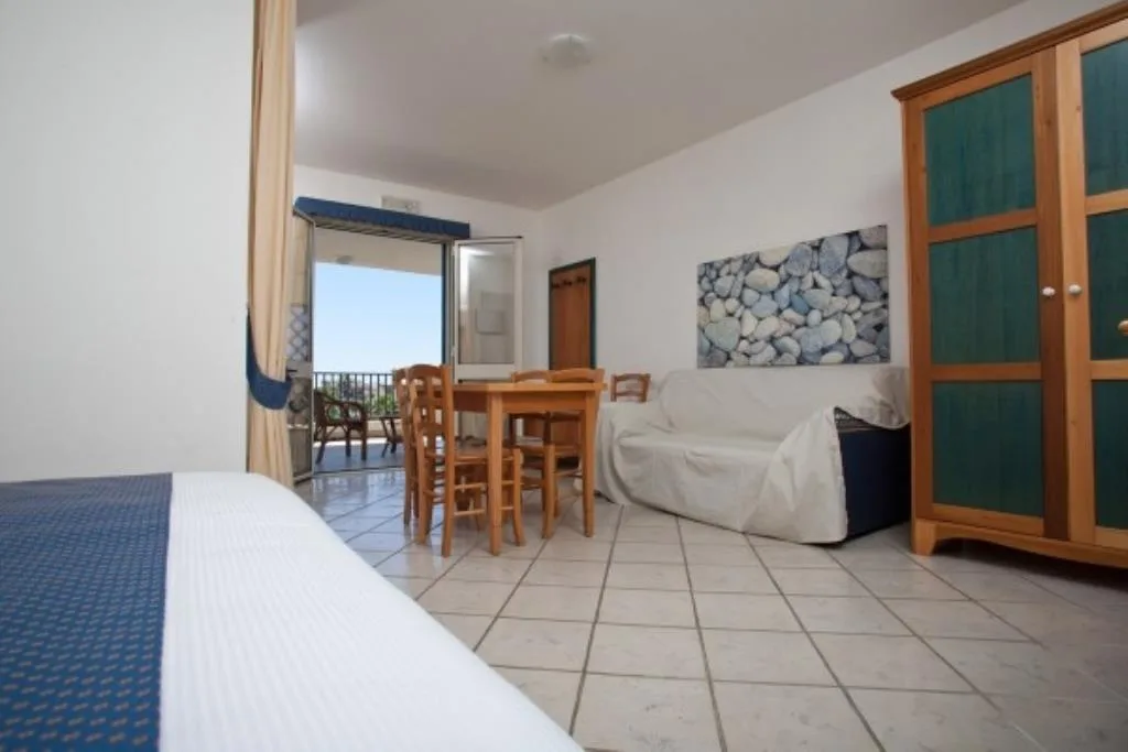 Monolocale con letto, divano, tavolo e balcone