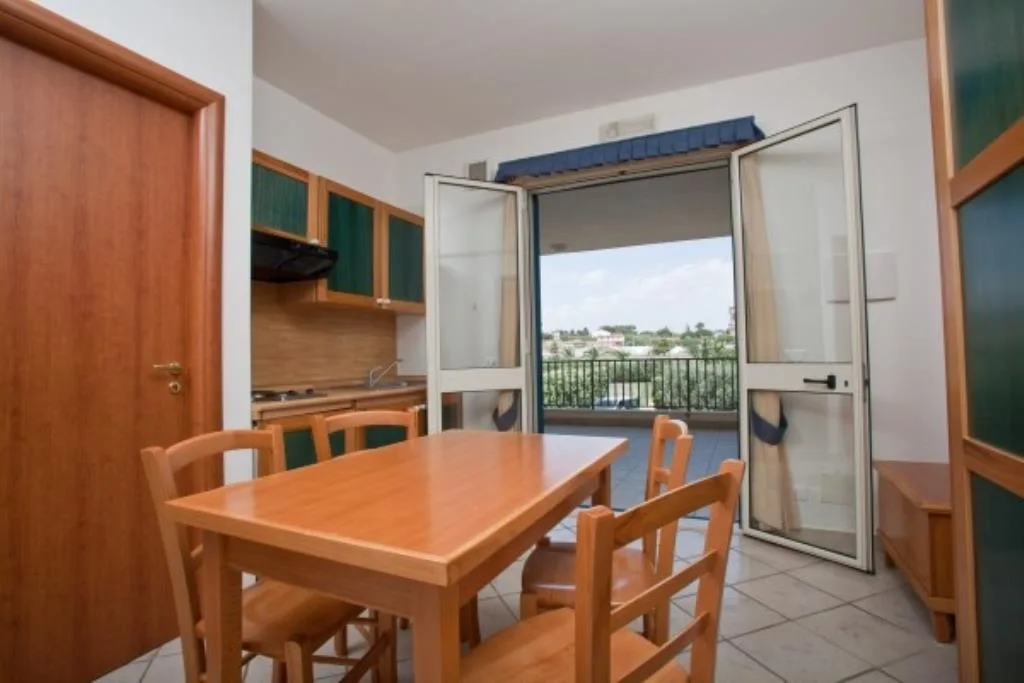 Cucina e zona pranzo con tavolo in legno e balcone