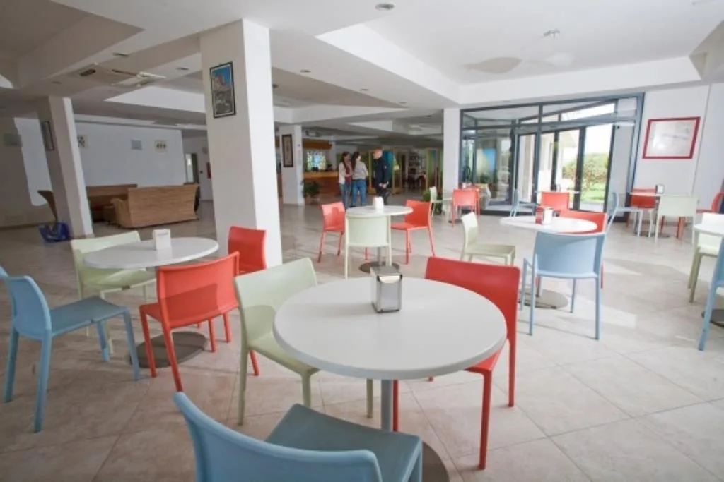 Sala comune con tavoli rotondi e sedie colorate