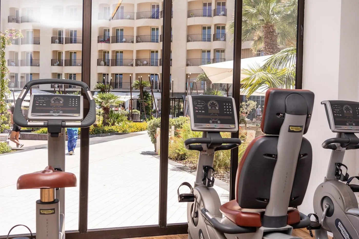 Sala fitness con cyclette e vista sul giardino e sulle camere dell'hotel
