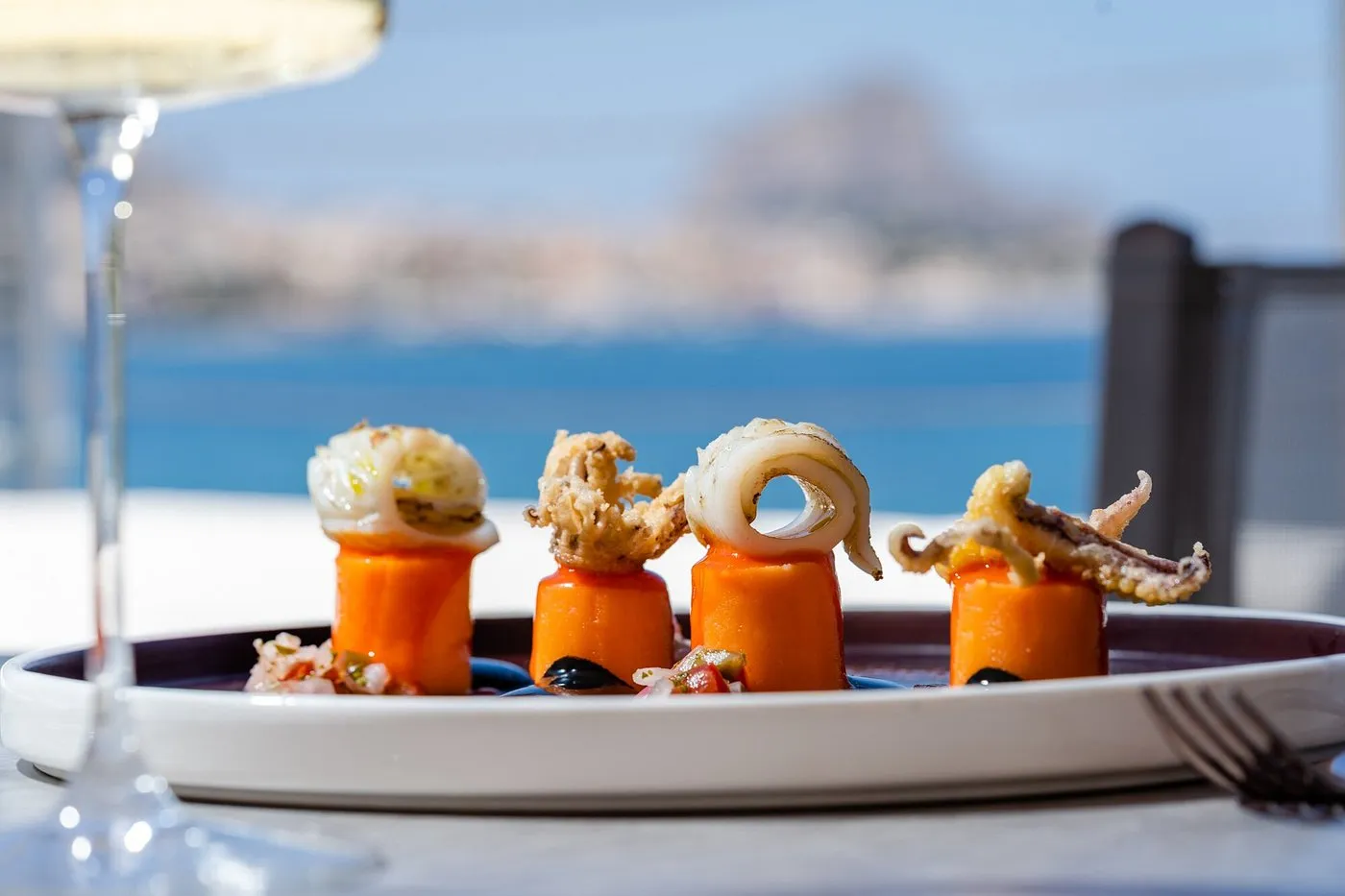 Piatto gourmet di calamari e polpo su mousse di carota con vista mare
