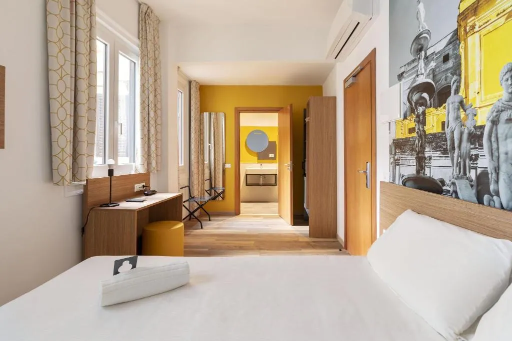 Camera con letto, scrivania, pareti gialle e ingresso al bagno