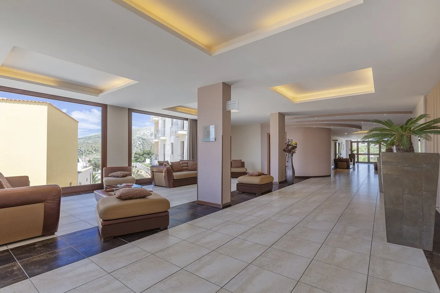 Ampia hall dell'hotel con divani in pelle, ampie vetrate e vista sulle colline