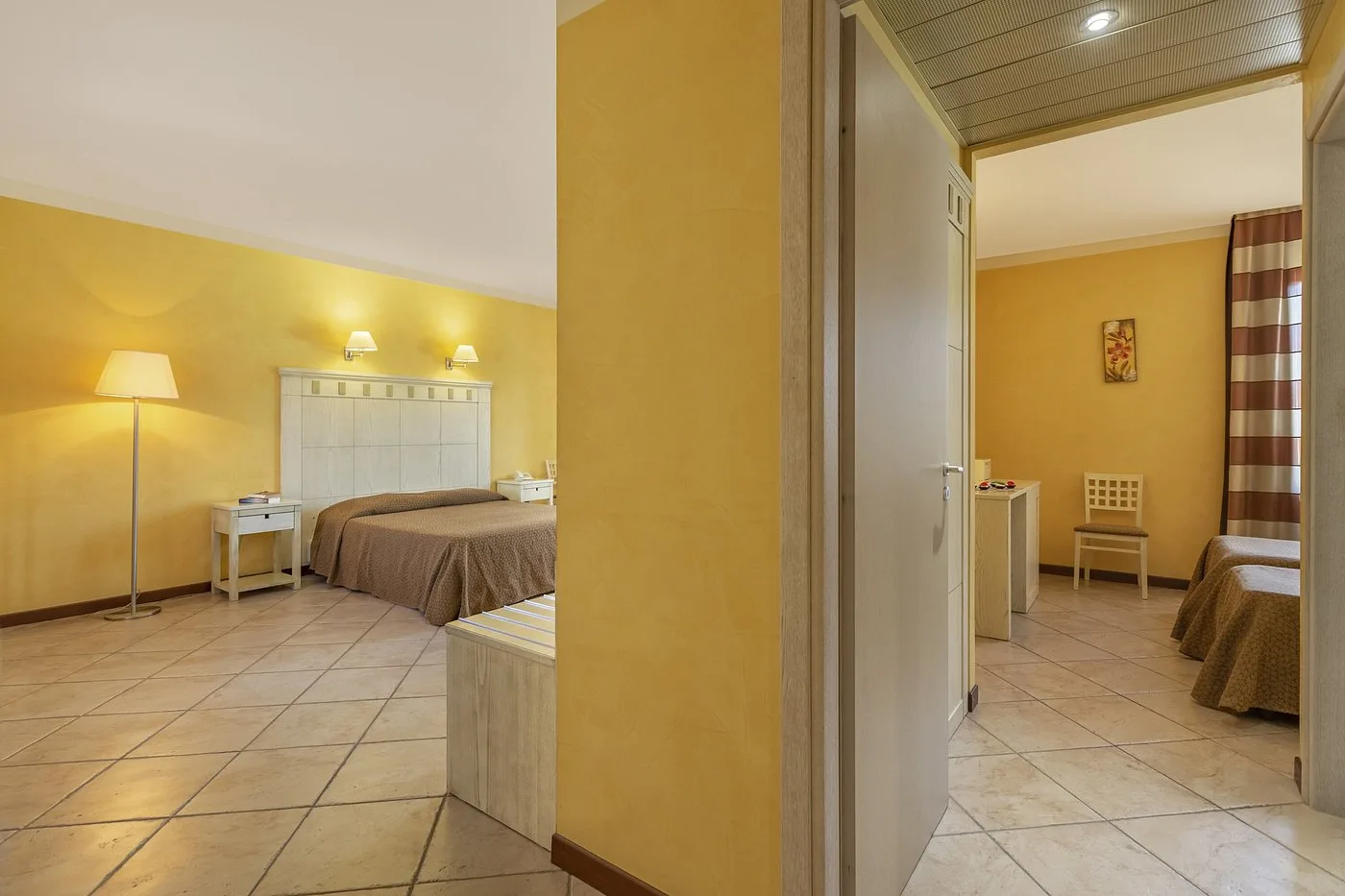 Camera familiare con letto matrimoniale e area separata, pareti gialle e pavimento in piastrelle
