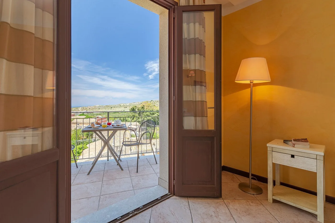 Camera con balcone affacciato sul paesaggio, lampada e scrivania con pareti gialle