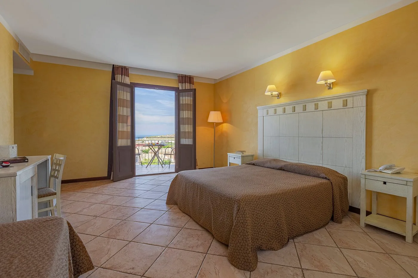 Camera matrimoniale spaziosa con pareti gialle e porta finestra con vista mare