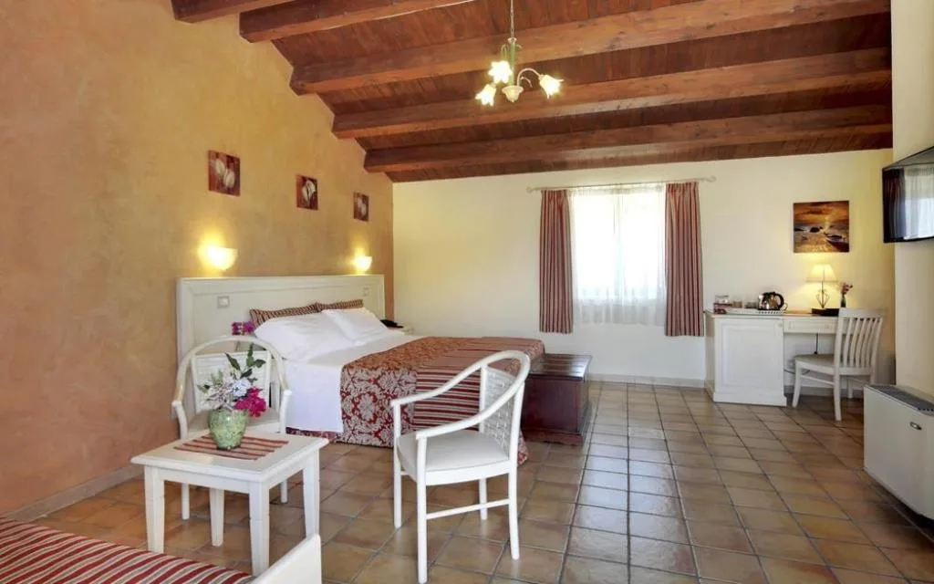Camera con travi in legno a vista, letto matrimoniale e zona relax con sedie