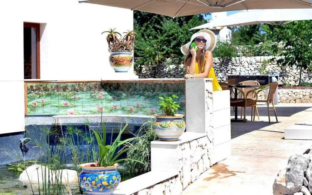 Terrazza esterna con laghetto ornamentale e vasi decorativi in ceramica siciliana