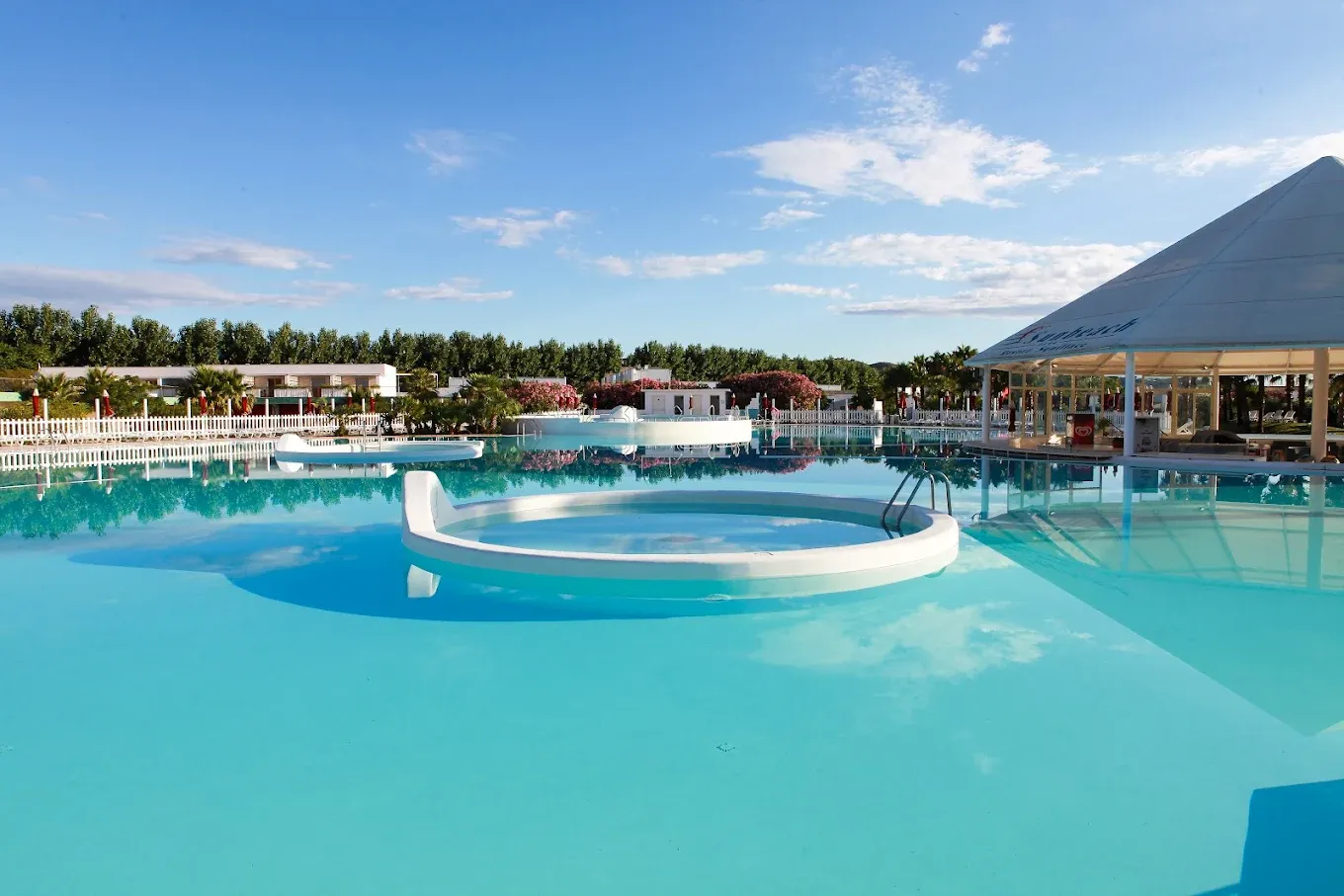 Piscina dalle acque turchesi con gazebo a piramide e cielo azzurro