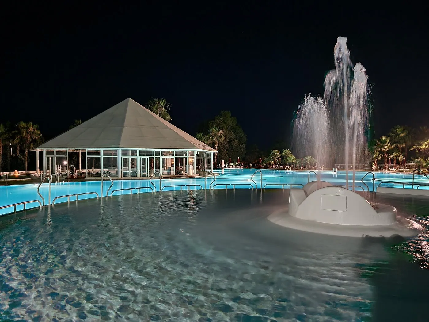 Piscina notturna con fontana zampillante e gazebo illuminato