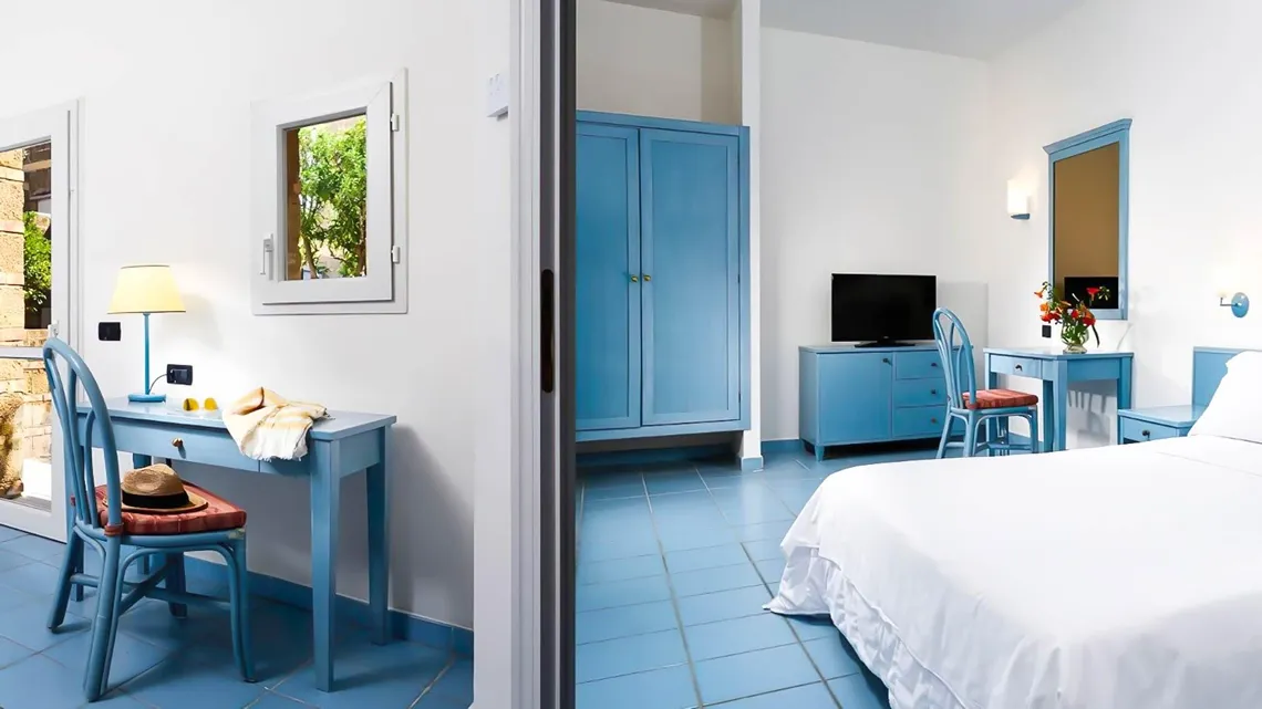 Camera con arredi azzurri, scrivania, armadio, TV e letto matrimoniale