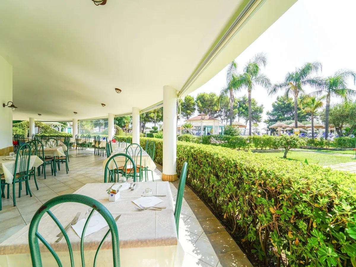 Terrazza ristorante coperta con tavoli apparecchiati e vista sul giardino